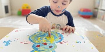 Kind malt einen Osterhasen mit Fingerfarbe